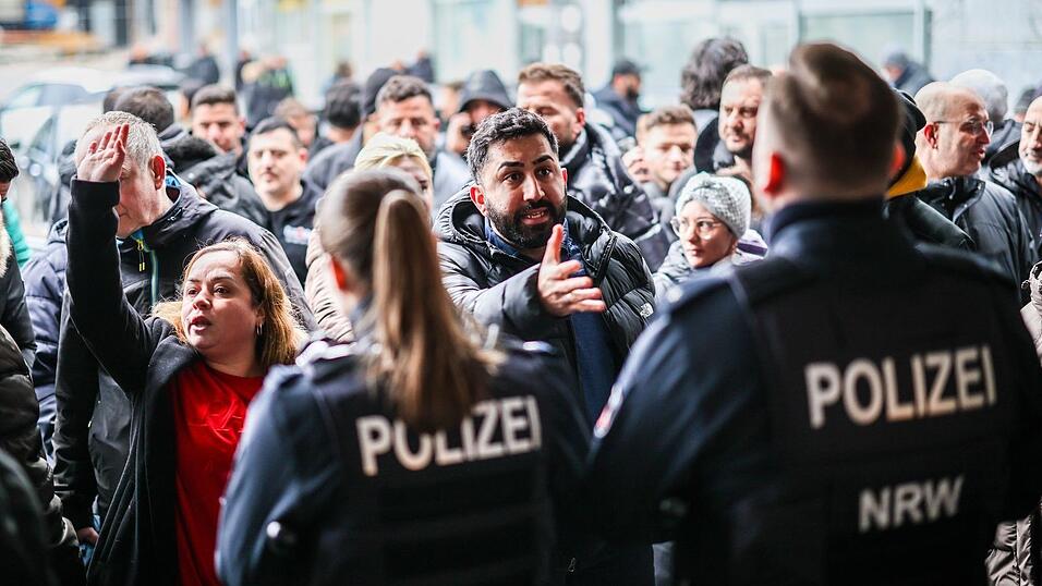 Aufgebrachte Kunden diskutieren vor der Sparkassenfiliale in Buer mit Polizeibeamten nach der R&auml;umung des Vorraums der Filiale.