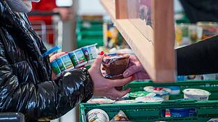 Eine Kundin (l) der Tafel Coburg bekommt Joghurt und Pudding. Der Landesverband Tafel Bayern e. V. besteht aus insgesamt 171 Mitgliedstafeln. (Archivbild)