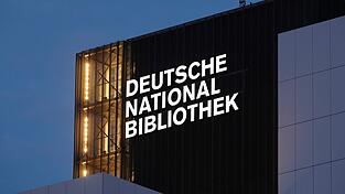 Der Schriftzug 'Deutsche Nationalbibliothek' (DNB) leuchtet an einem 55 Meter hohen Gebäude der früheren Deutschen Bücherei. (Archivbild)