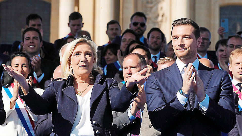 Marine Le Pen feiert bei einer Kundgebung mit ihrem Ziehsohn und m&ouml;glichen Nachfolger Jordan Bardella auf einer B&uuml;hne.