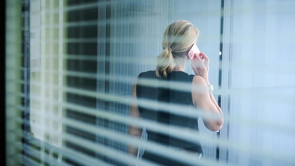 Eine Frau steht in einem Büro und telefoniert.
