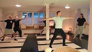 Der Körper aufrecht, die Arme ausgestreckt: Unter dem Blick von Yogalehrer Christian Wolf (rechts) machen die Männer den Krieger.