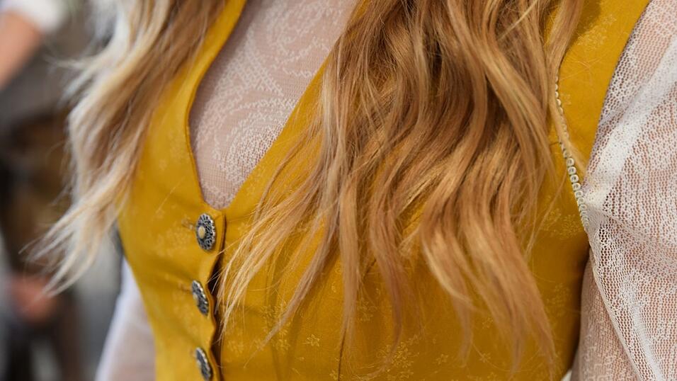 Das Vintage-Dirndl hat einen V-Ausschnitt. Die langärmelige Spitzenbluse ist hochgeschlossen.