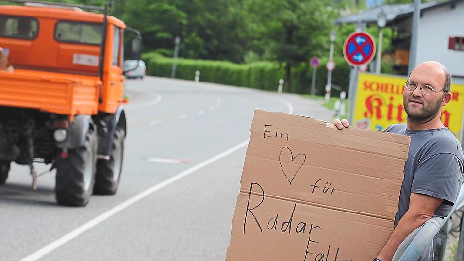 Tobias Anzenberger hat sich mit seiner Papp-Warnung an der Straße platziert. Er muss das Schild halten, sonst wäre es eine Ordnungswidrigkeit. Tobias Anzenberger hat sich mit seiner Papp-Warnung an der Straße platziert. Er muss das Schild halten, sonst wäre es eine Ordnungswidrigkeit.