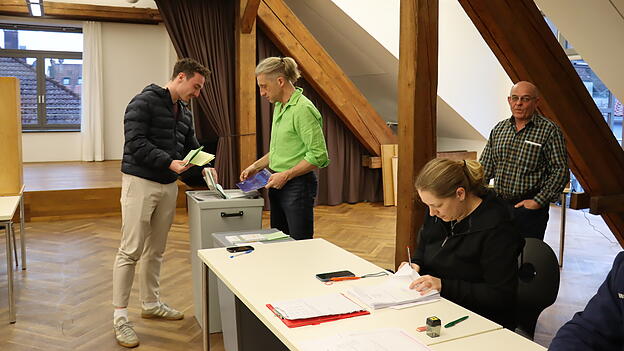 Alexander Liebl (links) wirft als einer der letzten W&auml;hler kurz vor 18 Uhr im W&ouml;rther B&uuml;rgersaal seine Stimmzettel in die Urnen.