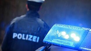 Ein Polizist steht im Regen vor einem Streifenwagen dessen Blaulicht aktiviert ist. Foto: Karl-Josef Hildenbrand/dpa/Archiv