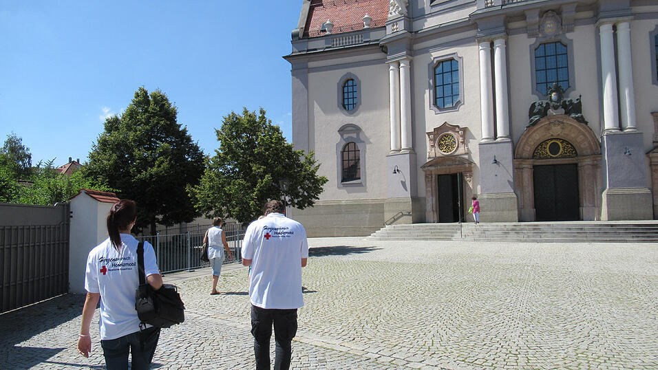Die Helfer des BRK Herzenswunsch-Hospizmobils bringen Frau P. in die Basilika.