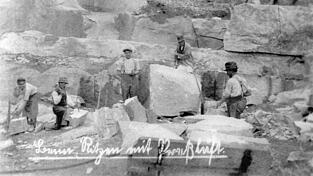 Das Foto aus dem Jahr 1904 zeigt das Ritzen eines Granitblocks mit Pressluft (Zweiter von rechts) zur Vorbereitung für das Sprengen. Andere Arbeiter gehen mit Hammer und Meißel ans Werk. Das Foto aus dem Jahr 1904 zeigt das Ritzen eines Granitblocks mit Pressluft (Zweiter von rechts) zur Vorbereitung für das Sprengen. Andere Arbeiter gehen mit Hammer und Meißel ans Werk.