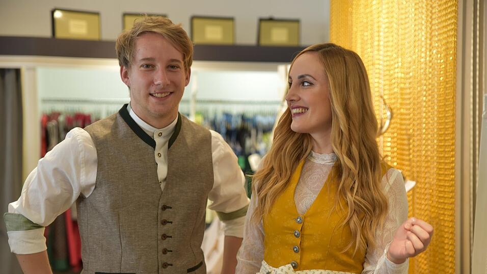 Das senfgelbe Dirndl trägt man beispielsweise in Kombi mit einer langärmeligen Spitzenbluse. Das Outfit in Lederhose & Co. ist farblich abgestimmt.