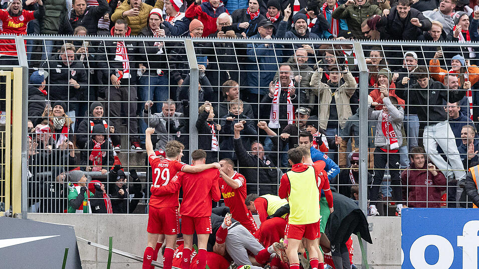 Die Regensburger feiern ihren Last-Minute-Treffer vor den mitgereisten Fans im Gr&uuml;nwalder Stadion.