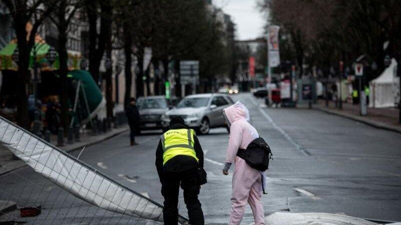 Ein Ordner und ein verkleideter Narr stehen in Düsseldorf an einem Bauzaun, der durch den Sturm umgeweht worden ist. Ein Ordner und ein verkleideter Narr stehen in Düsseldorf an einem Bauzaun, der durch den Sturm umgeweht worden ist.