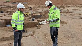 Grabungsleiter Benjamin Gademann (rechts) erklärt Tennet-Pressesprecher Johannes Prechtl, wie Pfostengruben und Stakenstandspuren entstehen.
