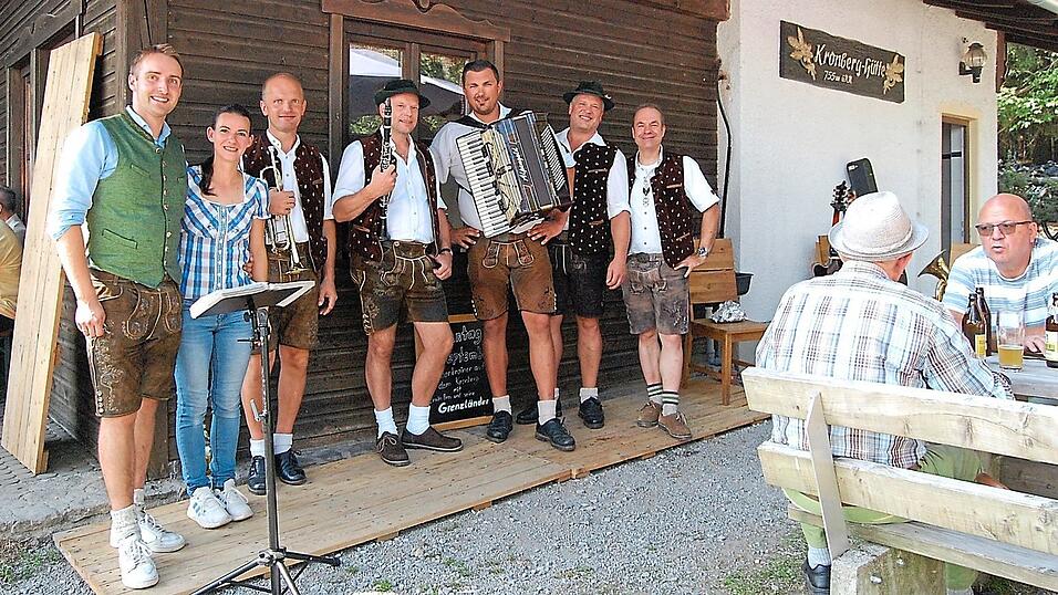Die H&uuml;ttenwirte Peter und Monika Kuen (v.l.) und die Grenzl&auml;nder-Musikergruppe vor der gro&szlig;en Kronbergh&uuml;tte des Waldvereins Blossersberg.
