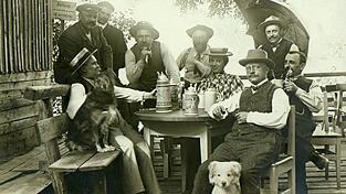 Das Biergartenverbot f&uuml;r Hunde wurde anscheinend manchmal nicht ganz so ernst genommen, wie hier auf dem Bild &bdquo;Gesellschaft mit Hunden im Biergarten der Wunderm&uuml;hle auf dem Gst&uuml;tt&ldquo; von 1910.