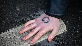 Ein Klimaaktivist hat sich mit der Hand auf den Asphalt geklebt. Ein Klimaaktivist hat sich mit der Hand auf den Asphalt geklebt.