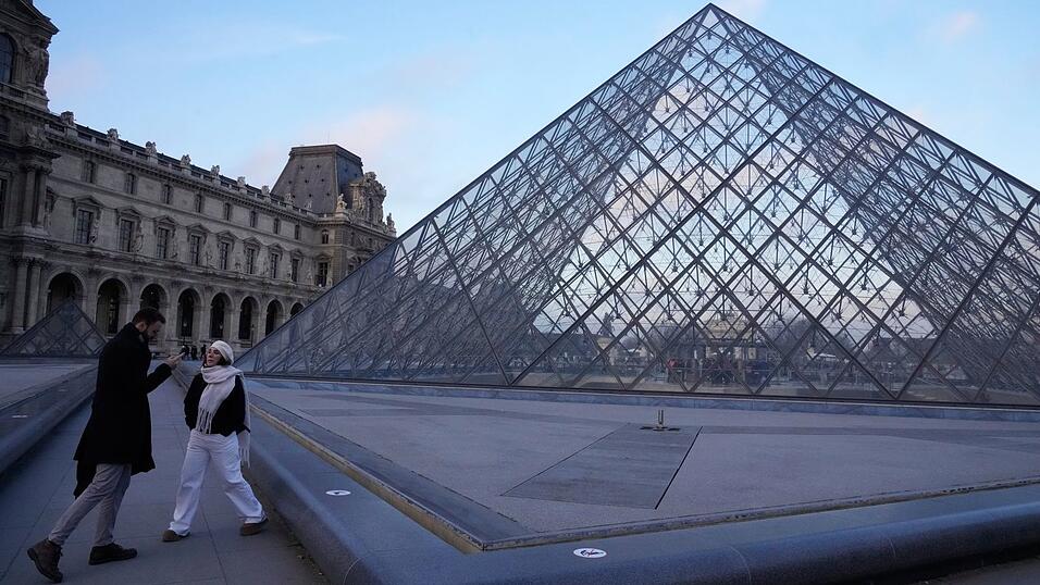 Menschen stehen an der Pyramide des Louvre-Museums am Montagmorgen. Menschen stehen an der Pyramide des Louvre-Museums am Montagmorgen.
