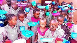 Kinder in Shirango mit dem neuen Geschirr warten auf das Frühstück.