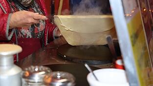Vorsichtig hebt Hahn mit einem metallenen Pfannenwender den dampfenden Teig von der heißen Platte. Vorsichtig hebt Hahn mit einem metallenen Pfannenwender den dampfenden Teig von der heißen Platte.