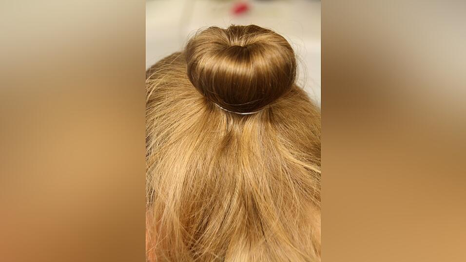 3. Sie legt die Haare &uuml;ber das Kissen und fixiert sie dort mit einem Gummi.