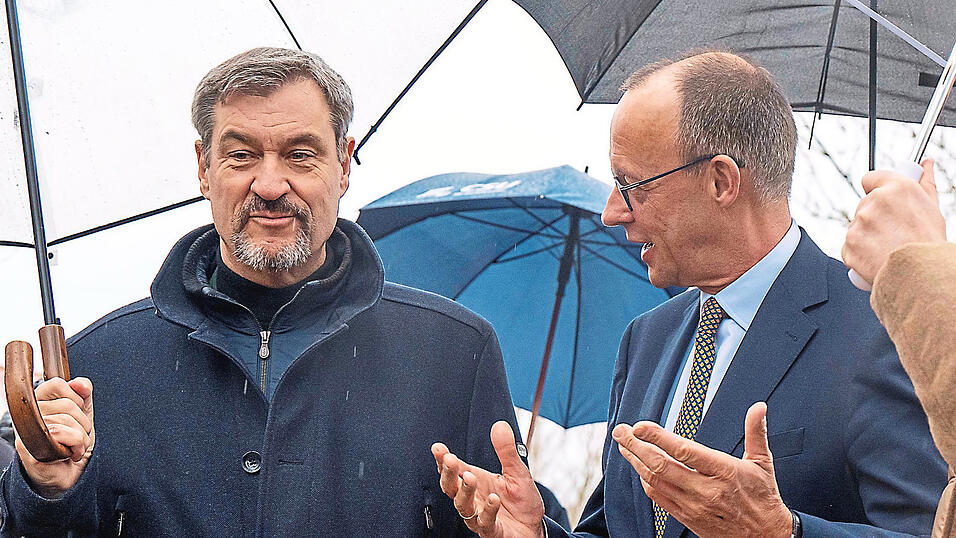 Knapp 15 Minuten stand Markus S&ouml;der (l.) im Regen und wartete auf Friedrich Merz.