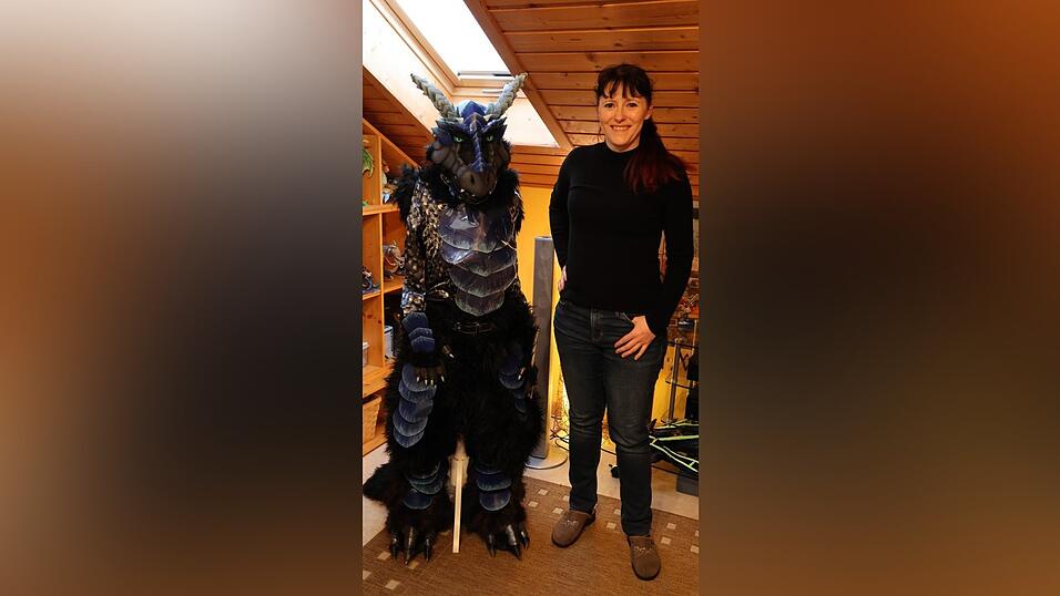 Tina Koller neben einem schwarzen Drachenanzug in ihrem Arbeitszimmer.