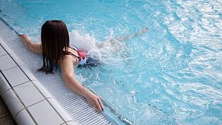 Wellness im Wasser: Eine Besucherin einer Therme sitzt an einer Sprudeld&uuml;se.