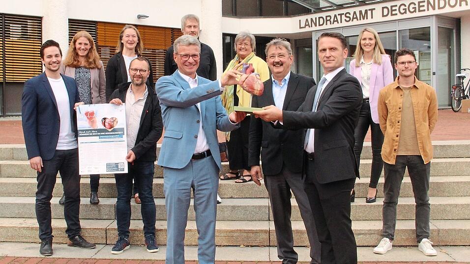 Bei der Vorstellung der Herzwoche und allen beteiligten Kooperationspartnern (hinten, v. l.): Rainer Unrecht von der 'Gesundheitsregion plus Landkreis Deggendorf', Franziska Ittameier (Volkshochschule), Maria Boyen (Amt f&uuml;r Ern&auml;hrung, Landwirtschaft und Forsten), Florian Seidl (BRK-Kreisverband), Tobias Zitzelsberger und Waltraud Kraus (Gesundheitlicher Sozialdienst), Claudia Weber (AOK) und Robert Weindl (Wohl-Leben GmbH). Vorn im Bild Landrat Bernd Sibler sowie Professor Dr. Michael Quintel und Edmond Skenderaj vom Donau-Isar-Klinikum Deggendorf mit dem Modell eines Herzens.