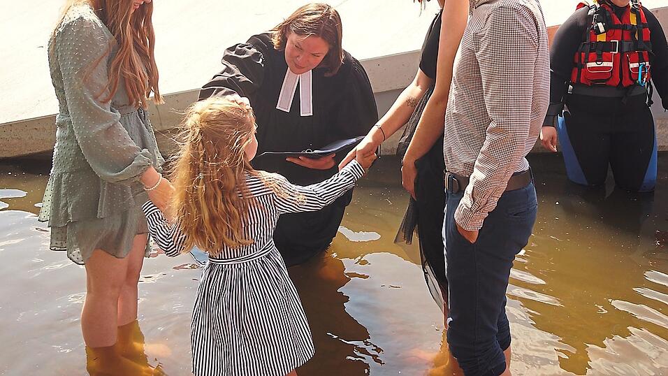 Im Wasser stehend spendet Pfarrerin Lisa Hacker das Taufsakrament.