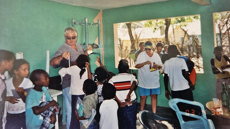 Marjorie (3. v.r.) und Jim Hughes (Mitte) brachten bei ihren jährlichen Reisen in die Dominikanische Republik Geschenke wie Bleistifte, Kugelschreiber und Lineale für Schulkinder mit. Nach ihrer Auswanderung in die Karibik unterstützten sie die Buben und Mädchen weiterhin. Diese Aufnahme entstand kurz nach ihrem Umzug. Marjorie (3. v.r.) und Jim Hughes (Mitte) brachten bei ihren jährlichen Reisen in die Dominikanische Republik Geschenke wie Bleistifte, Kugelschreiber und Lineale für Schulkinder mit. Nach ihrer Auswanderung in die Karibik unterstützten sie die Buben und Mädchen weiterhin. Diese Aufnahme entstand kurz nach ihrem Umzug.