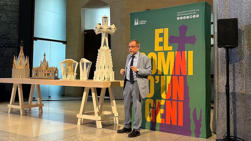 Der leitende Architekt der Sagrada Familia, Jordi Faulí, erklärt vor einem großen Poster den Aufbau des großen Kreuzes aus Deutschland für den Hauptturm der Basilika.