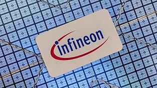 Das Infineon-Logo klebt auf einem Wafer im Showroom des Unternehmens. Foto: Peter Kneffel/dpa/Archivbild