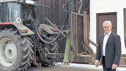 Ein B&uuml;rgermeister steht im Anzug vor seinen Ger&auml;tschaften. Angstl verbindet verschiedene Rollen miteinander: B&uuml;rgermeister, Landwirt, Gastwirt und Familienmensch.