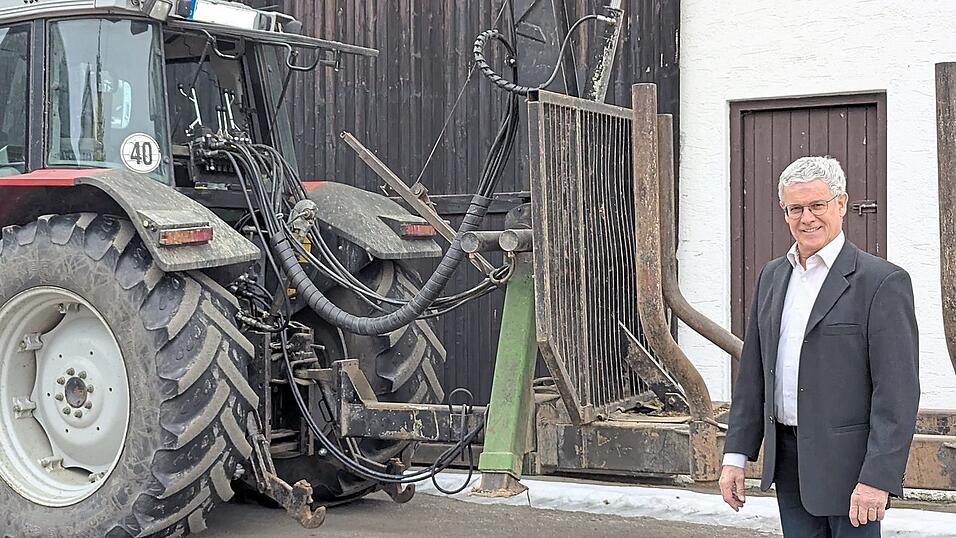 Ein B&uuml;rgermeister steht im Anzug vor seinen Ger&auml;tschaften. Angstl verbindet verschiedene Rollen miteinander: B&uuml;rgermeister, Landwirt, Gastwirt und Familienmensch.