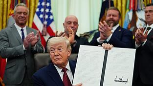 US-Pr&auml;sident Donald Trump h&auml;lt eine unterzeichnete Durchf&uuml;hrungsverordnung im Oval Office des Wei&szlig;en Hauses hoch.