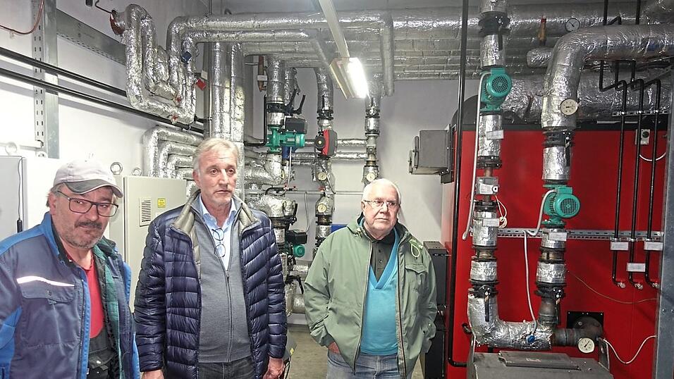 Reinhold Branghofer, Heizungsbauer aus Eidsberg (l.), erl&auml;uterte bei der F&uuml;hrung die Anlage mit dem Brenner f&uuml;r die Hackschnitzel und dem Verteilnetz in den Ort in zwei Kreisen.