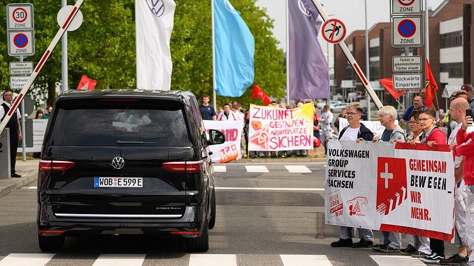 Ein VW-Bus mit VW-Vorstandschef Oliver Blume passiert die Demonstration von Besch&auml;ftigten am Werkstor des Standortes Zwickau.