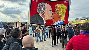 Demonstranten halten bei einer Kundgebung des Bündnisses «Eine Million Augenblicke für Demokratie» ein Banner, auf dem sich stilisiert US-Präsident Trump und Russlands Präsident Putin küssen. Demonstranten halten bei einer Kundgebung des Bündnisses «Eine Million Augenblicke für Demokratie» ein Banner, auf dem sich stilisiert US-Präsident Trump und Russlands Präsident Putin küssen.