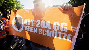 Ein Teilnehmer einer Demonstration der Letzten Generation hält ein Banner.