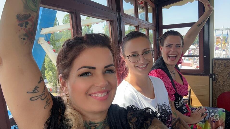 Verr&uuml;ckte Tattoo-Aktion im Riesenrad auf dem G&auml;ubodenvolksfest: Die beiden T&auml;towiererinnen Sina Frohnholzer (l.) und Erica Van Oorschot (r.) mit Yvonne Dallinger.