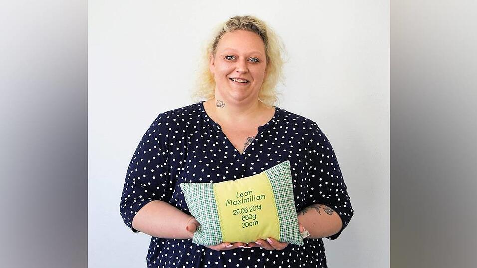 Stephanie Becher hält ein Kissen in der Hand, welches mit den Geburtsdaten ihres Sohnes Leon bestickt ist. Stephanie Becher hält ein Kissen in der Hand, welches mit den Geburtsdaten ihres Sohnes Leon bestickt ist.