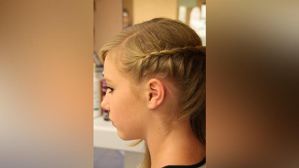 1. Hannah zieht einen Seitenscheitel und beginnt auf der Seite, auf der weniger Haare sind, schr&auml;g nach hinten (bis zur Mitte des Hinterkopfes) zu flechten. Dazu nimmt sie eine Haarpartie und teilt sie in drei Teile. Jeweils von unten nimmt sie immer wieder eine Str&auml;hne hinzu.