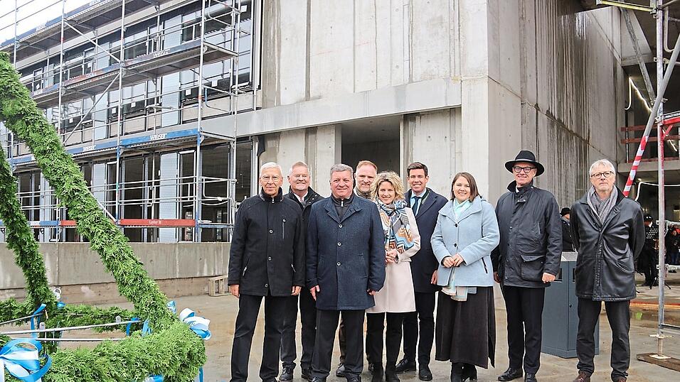 Udo Hebel (von links), Jürgen Eberwein, Christian Bernreiter, Peter Aumer, Astrid Freudenstein, Patrick Grossmann, Carolin Wagner, Walter Jonas und Gerhard Haslbeck neben dem Richtkranz vor dem entstehenden neuen Vorklinikum auf dem Campus der Uni Regensburg.