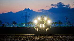 Ein Landwirt düngt in der Morgendämmerung ein Feld.