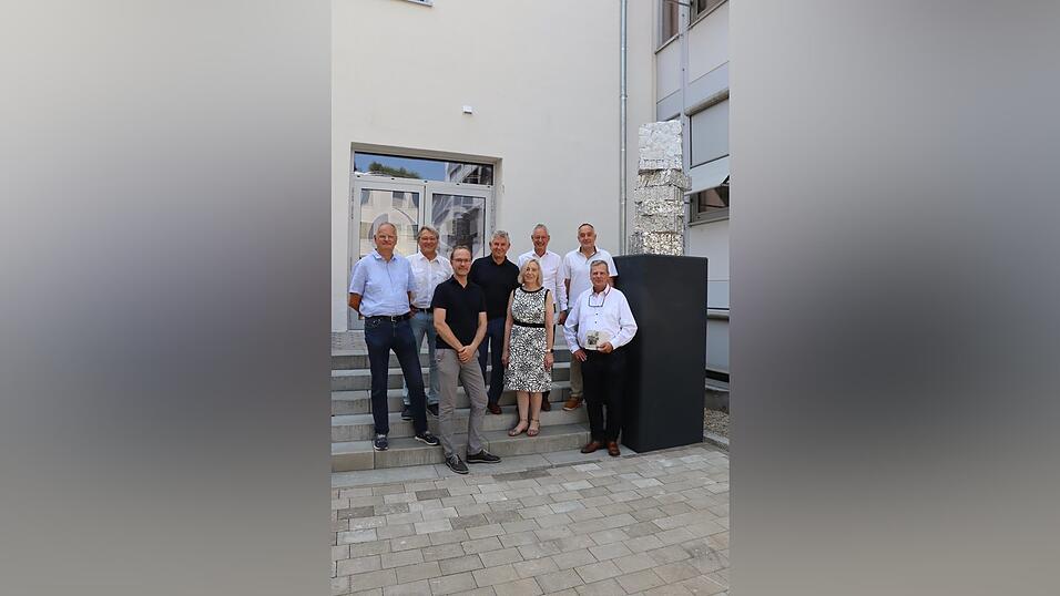 Rupert Buchner vom Hochbauamt (v.l.), Baureferent Oliver Vetter-Gindele, Hochbauamtsleiter Marko Kreißig, stellvertretender Landrat Ludwig Knott, Hermine Eckl, Leiterin der Staatlichen Berufsschule I, OB Markus Pannermayr, Kultur-Verwaltungsrat Andreas Fuchs und Künstler Markus Eberl neben dem Kunstwerk „Kompression“ - in Erinnerung an Josef Eberl, 2026, Aluminium. Rupert Buchner vom Hochbauamt (v.l.), Baureferent Oliver Vetter-Gindele, Hochbauamtsleiter Marko Kreißig, stellvertretender Landrat Ludwig Knott, Hermine Eckl, Leiterin der Staatlichen Berufsschule I, OB Markus Pannermayr, Kultur-Verwaltungsrat Andreas Fuchs und Künstler Markus Eberl neben dem Kunstwerk „Kompression“ - in Erinnerung an Josef Eberl, 2026, Aluminium.