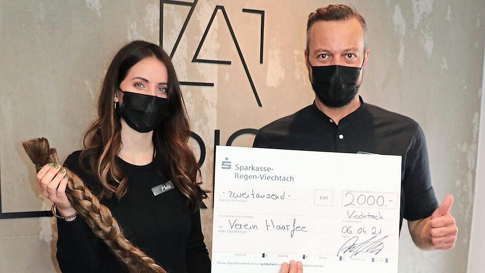 Die beiden Viechtacher Friseure Maria Kromm und Andy Larisch mit dem erst k&uuml;rzlich gespendeten Betrag und Z&ouml;pfen, aus denen Echthaar-Per&uuml;cken entstehen.
