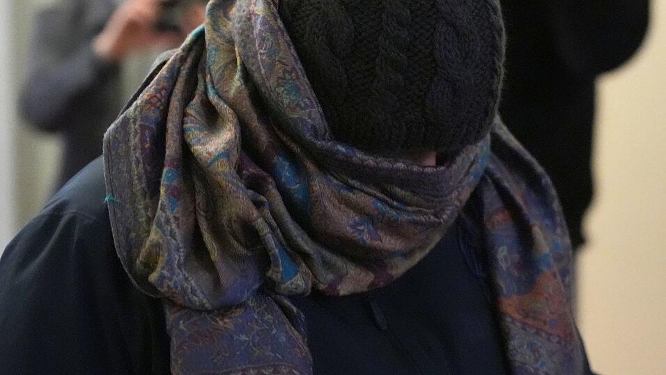 Eine Zeugin verl&auml;sst vermummt den Gerichtssaal.