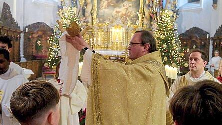 Stadtpfarrer Seidl zeigt das Jesuskind in alle Himmelsrichtungen.