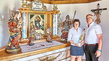 Das Ehepaar Berta und Helmut Müller mit der großen Einweihungskerze vor dem Altar der Marienkapelle. Das Kirschbaumholz des Altares stammt vom eigenen Hof.