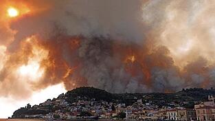 Rauch eines Waldbrandes steigt hinter einem Berghang in dem Ort Limni, auf der Halbinsel Euböa, etwa 160 Kilometer nördlich von Athen, auf.