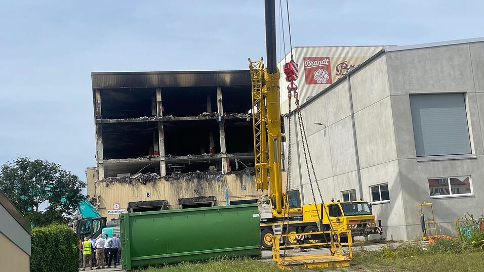 Autokran und Bagger stehen am Donnerstag noch vor der Lagerhalle. Jetzt &uuml;bernehmen die Brandermittler von Kripo und LKA.